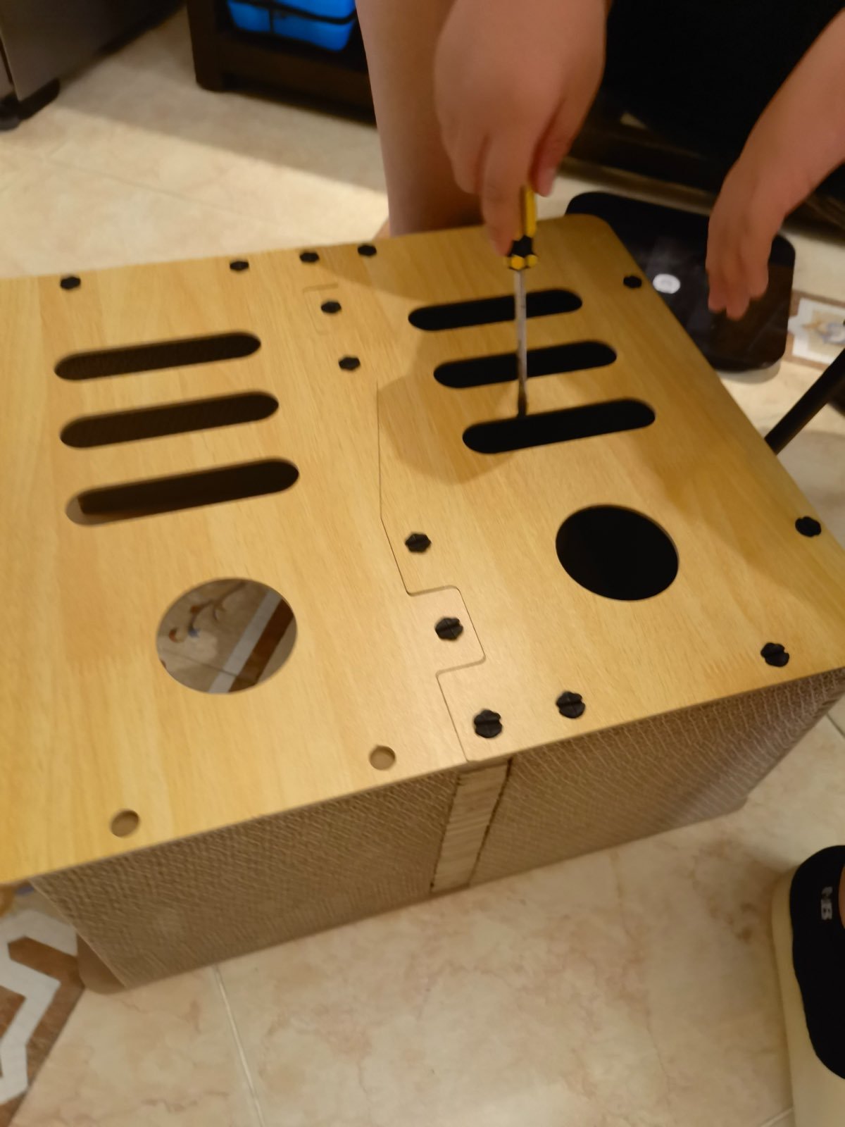 Assembling the wooden cat house with a screwdriver