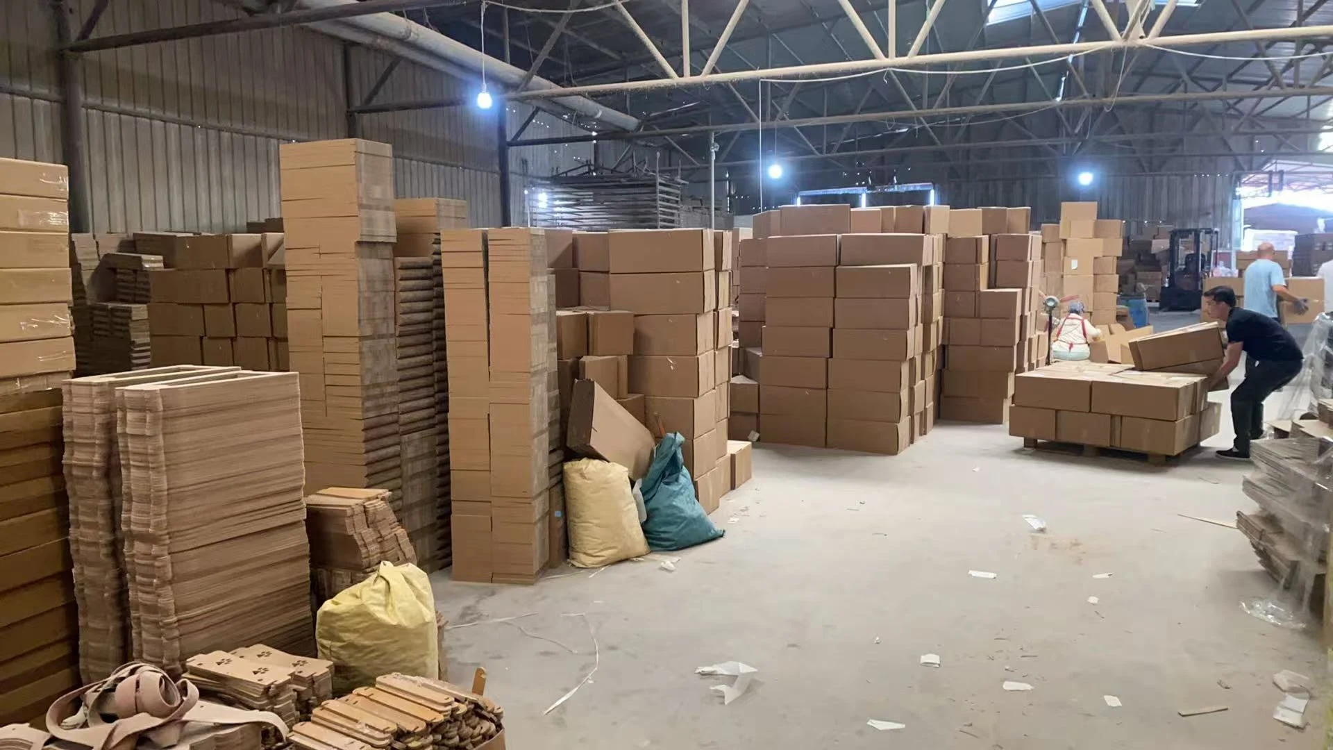 Packaging workshop with stacked cardboard boxes and workers preparing shipments